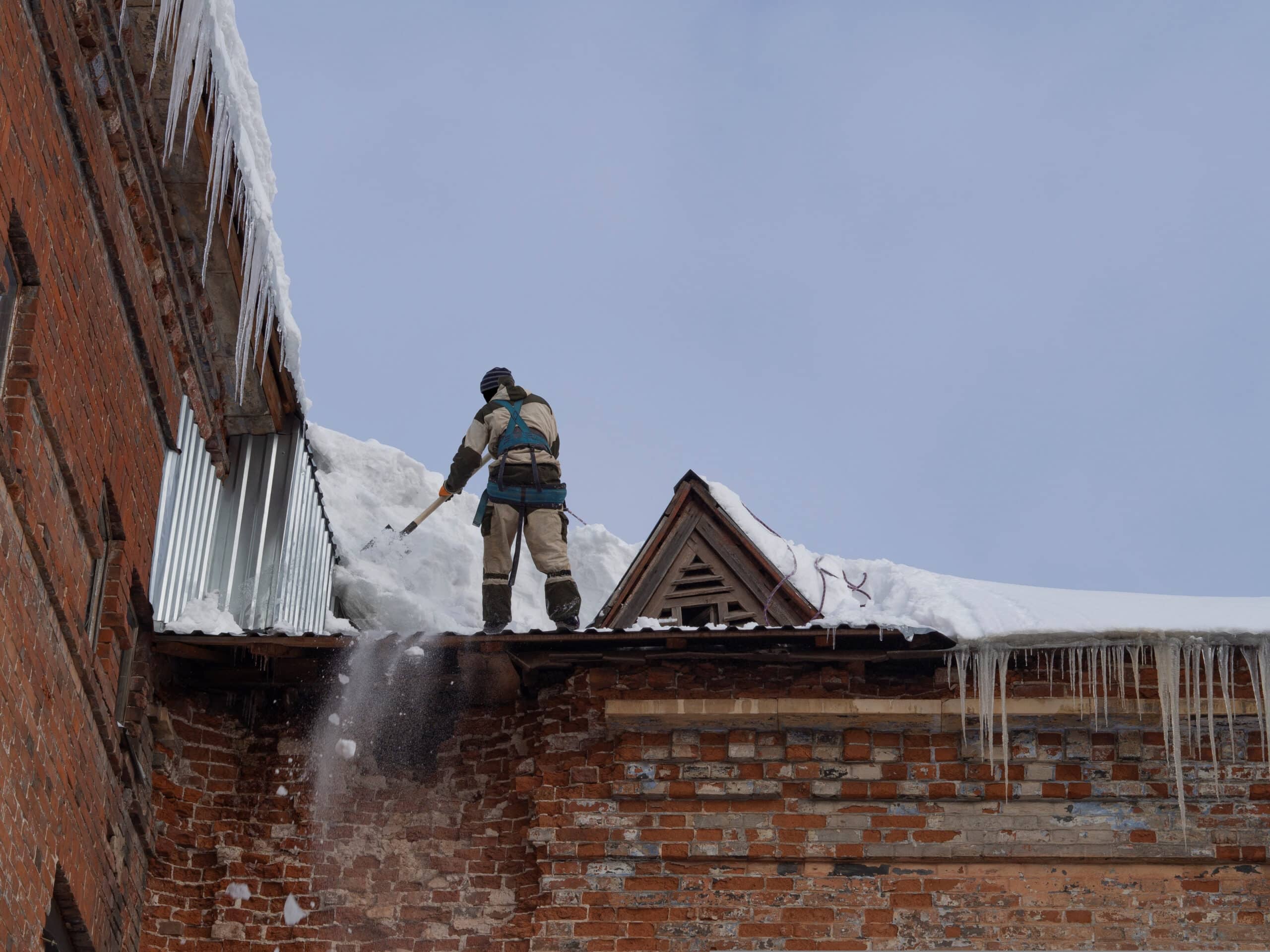 Man on roof removing snow